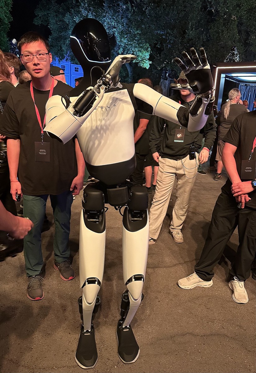 Tesla Optimus humanoid robot raising a hand among guests at the Tesla We, Robot event