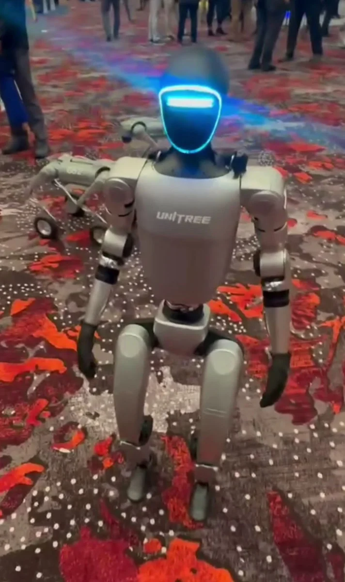 Unitree G1 humanoid robot standing on a patterned floor at a trade show