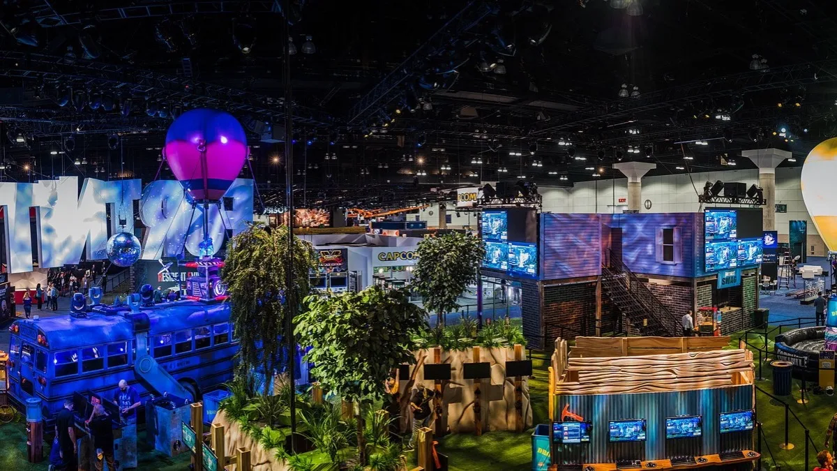 A large Fortnite convention booth with a themed battle bus, hot air balloon and rows of gameplay screens