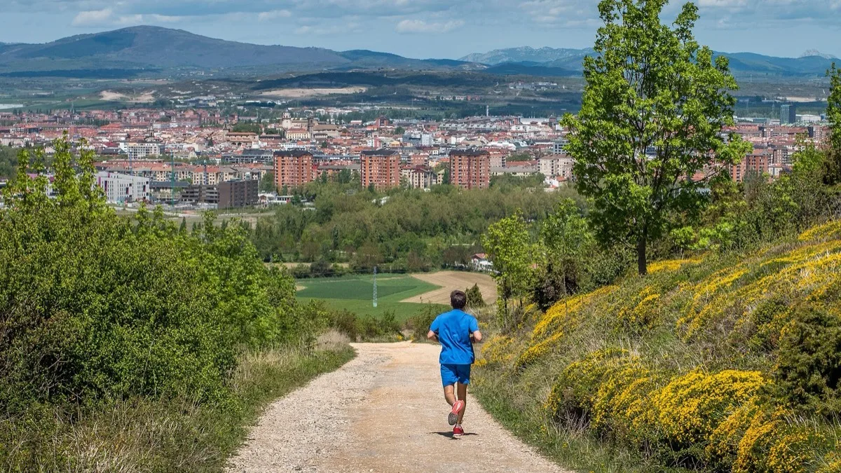 A runner on a gravel trail above a city, illustrating Spotify's new tempo-matched Running Mode