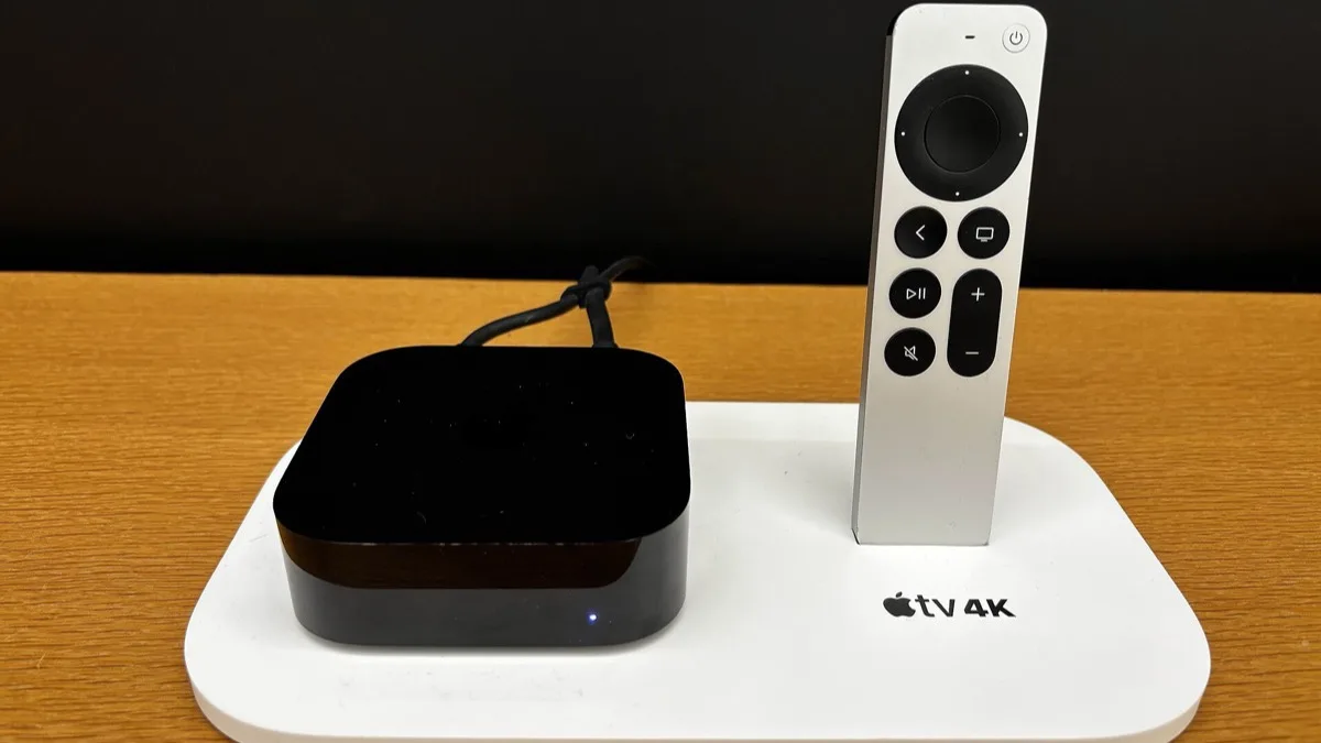 The current Apple TV 4K set-top box next to its Siri Remote on a wooden table