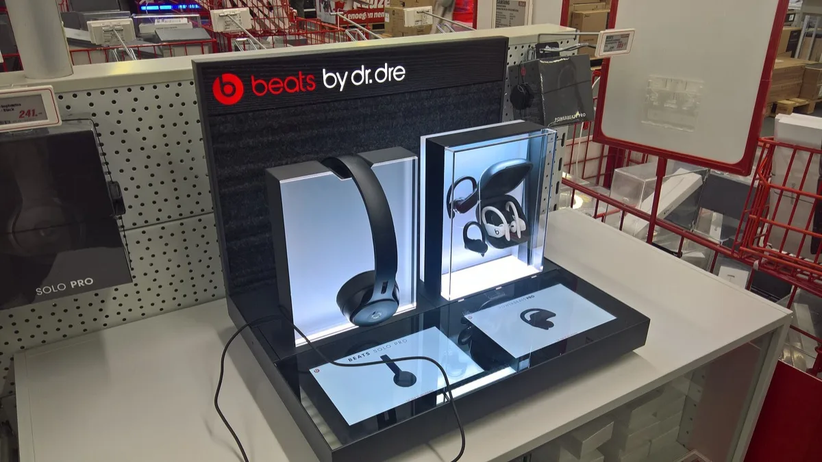 A retail display case showing Beats by Dr. Dre headphones and earbuds on a store shelf