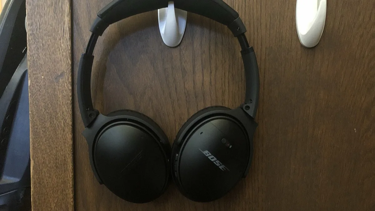 Black Bose QuietComfort over-ear noise cancelling headphones resting against a wooden surface