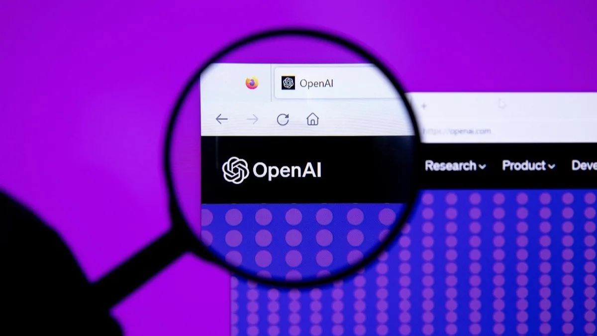 A magnifying glass held over a computer screen showing the OpenAI website and logo