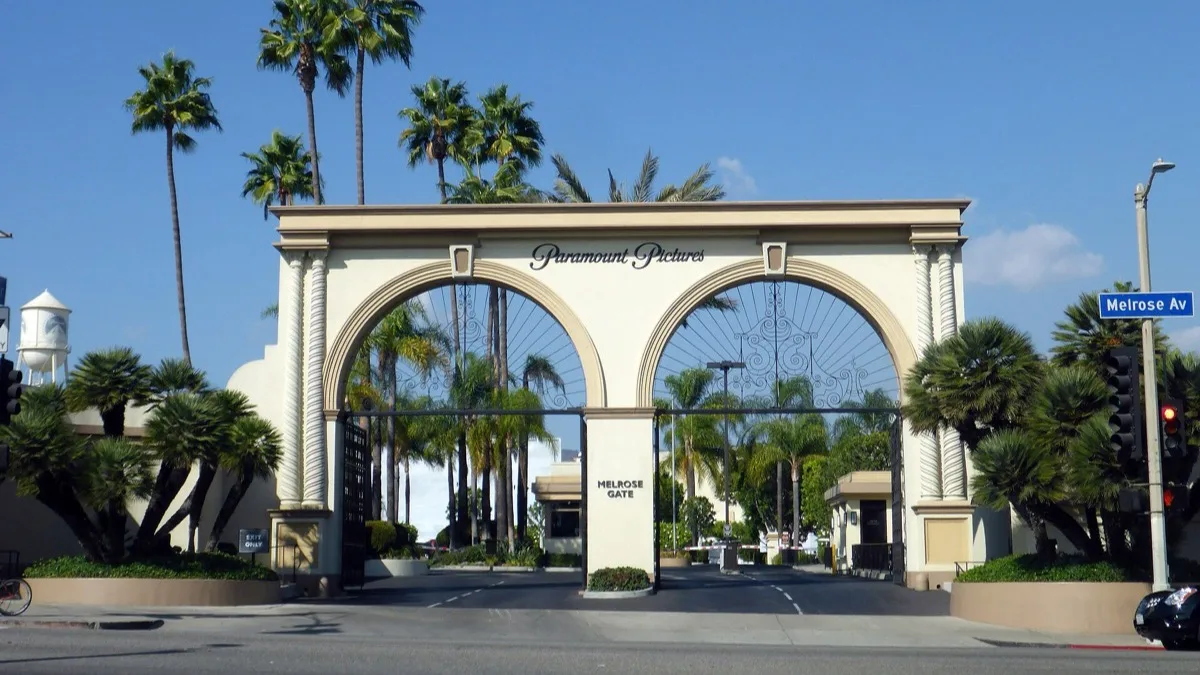 The Melrose Gate entrance arch at the Paramount Pictures studio lot in Los Angeles under a clear blue sky
