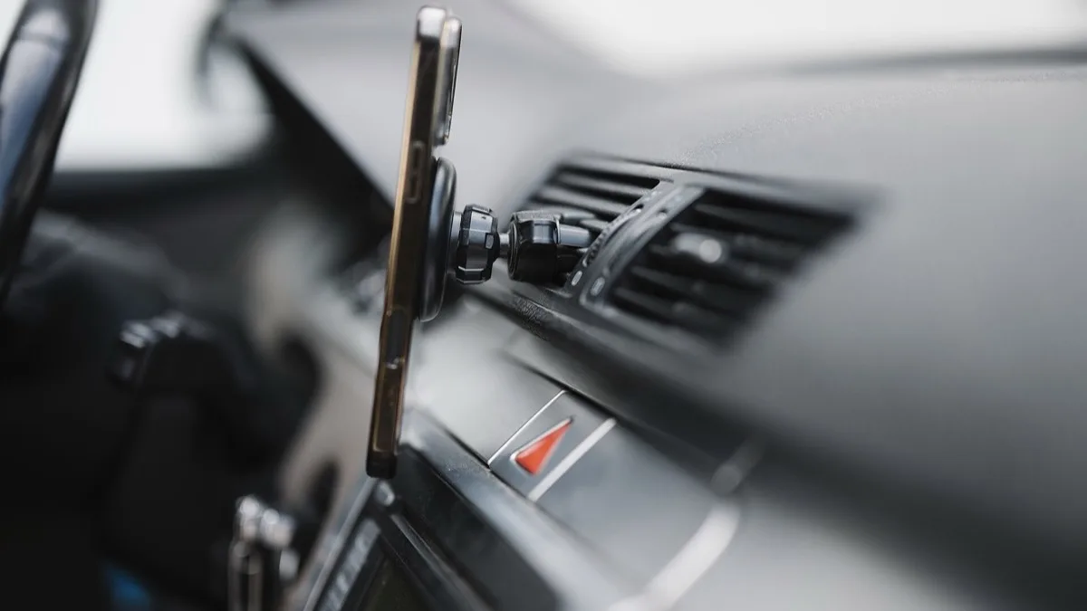 A smartphone mounted on a car dashboard next to the air vents, used for in-car navigation