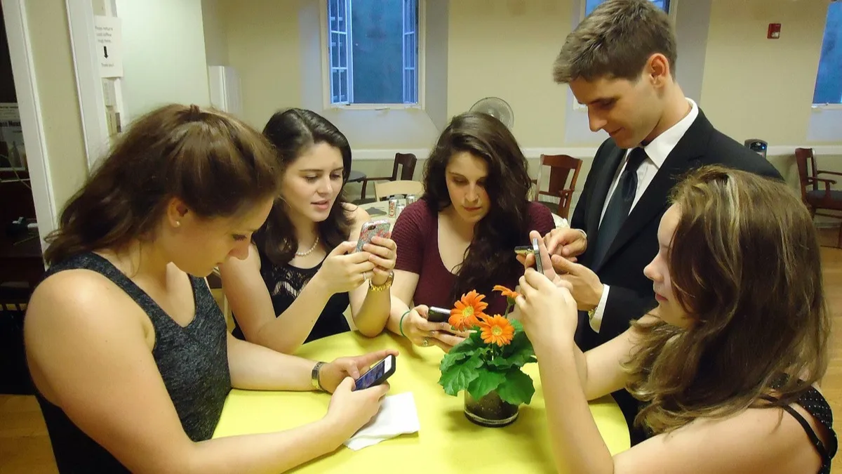 A group of people holding smartphones and typing with their thumbs