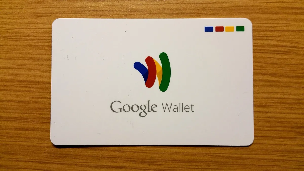 A white Google Wallet card with the Google Wallet logo resting on a wooden surface
