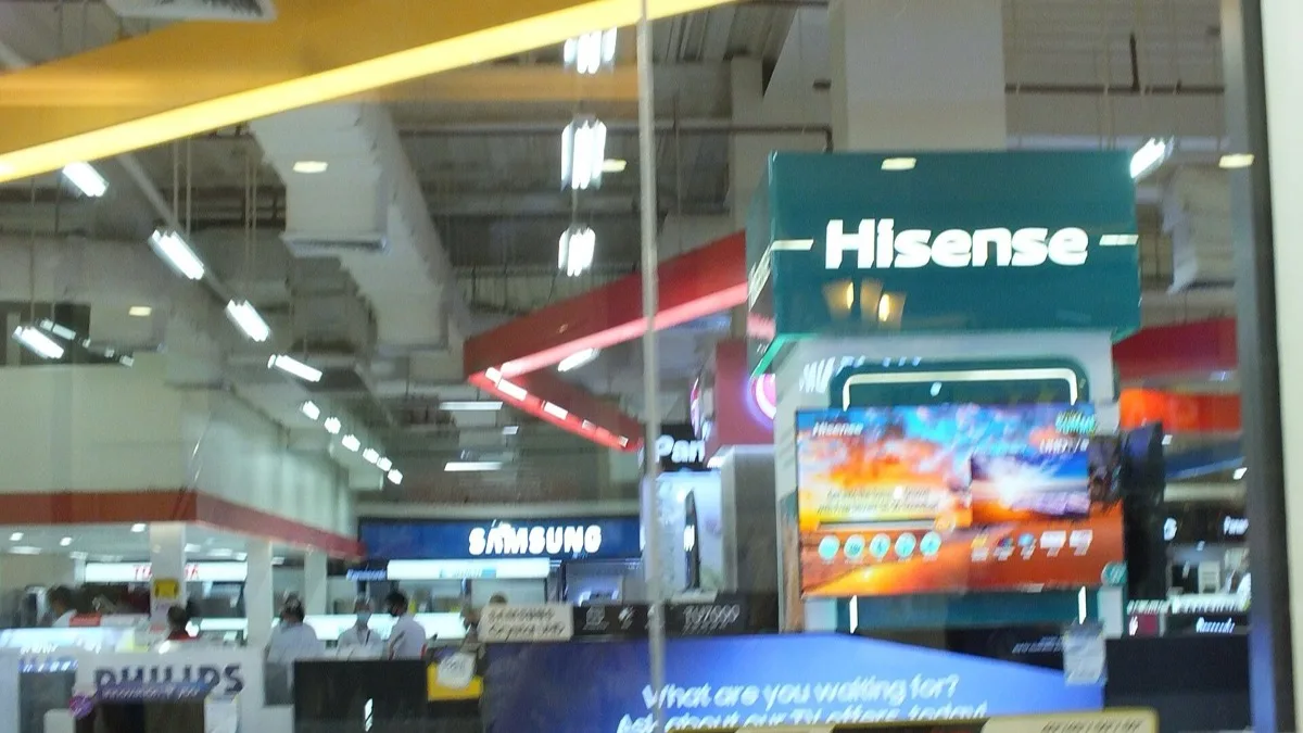 Hisense televisions on display at an electronics retailer, with a Hisense-branded stand above the screens