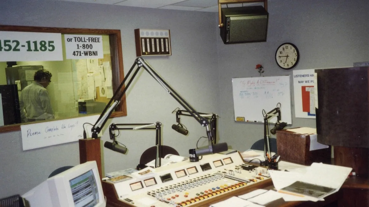 A radio broadcast studio with boom microphones over a mixing console