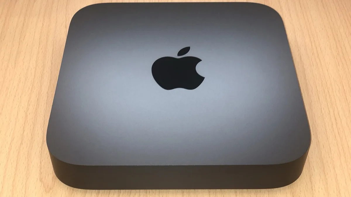 A Mac mini desktop computer with its Apple logo facing up on a wooden table
