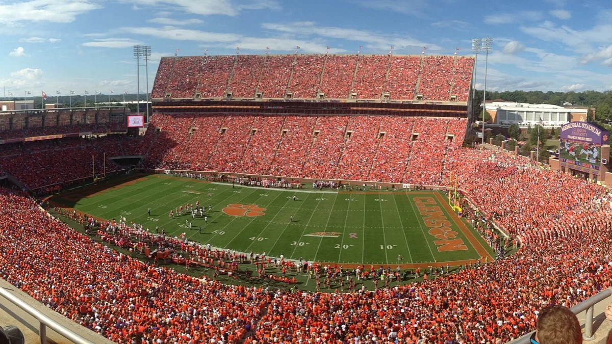 A packed American football stadium seen from the upper deck, with the game under way on the field below