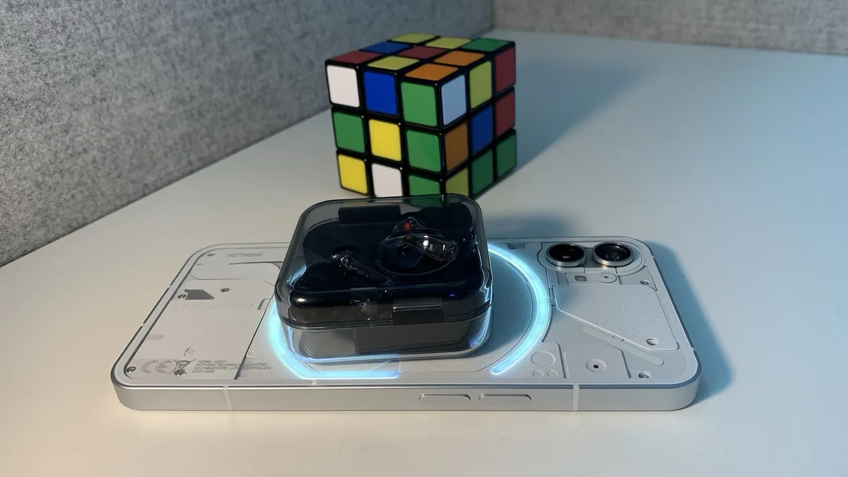 Nothing Phone (1) with its transparent back and Glyph lighting visible, earbuds case resting on top