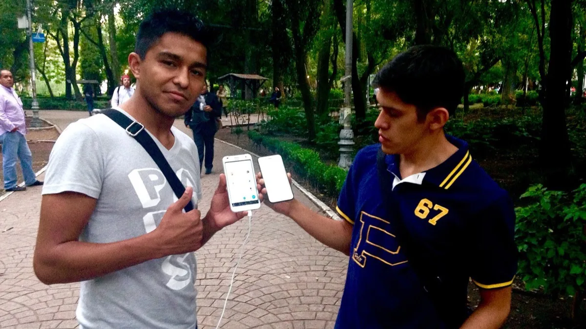 Two Pokemon GO players standing in a city park comparing what is on their smartphone screens