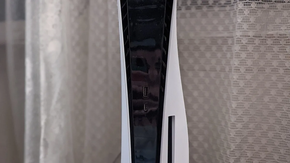 A white PlayStation 5 disc console standing upright, with the USB ports on its front panel visible