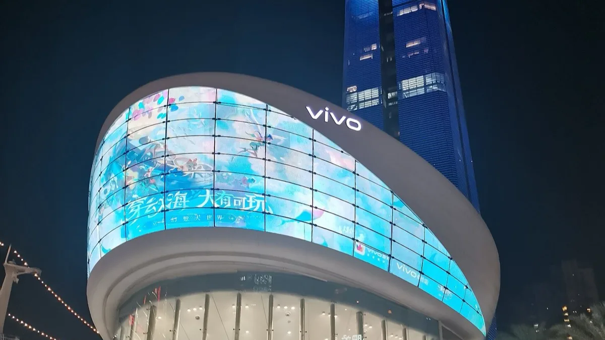A vivo flagship store lit up at night, its curved facade wrapped in LED screens under the vivo logo