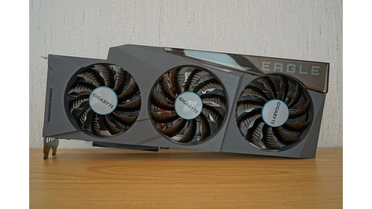A Gigabyte GeForce RTX 3090 Eagle graphics card with three fans standing on a wooden desk
