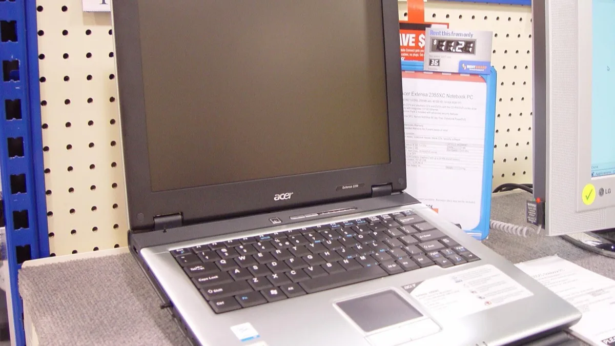 An Acer notebook computer open on a retail display shelf next to its spec card