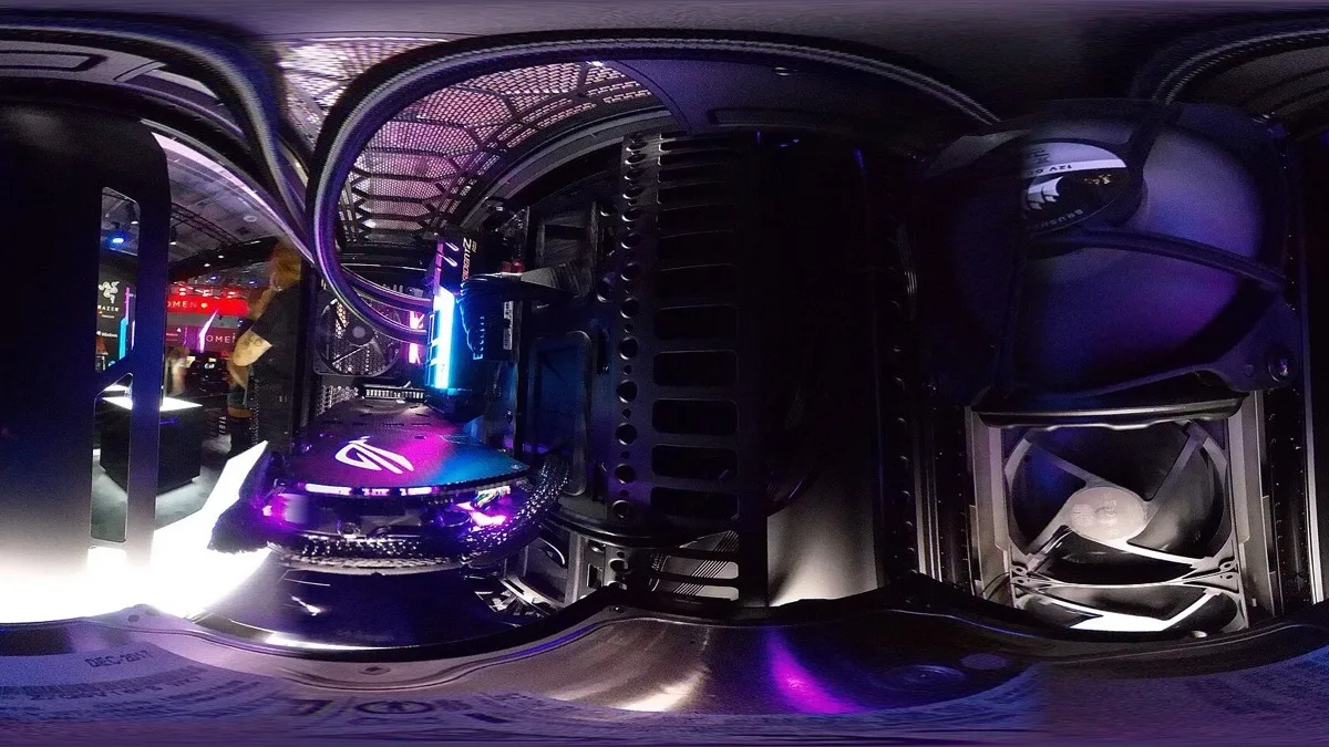 The interior of an RGB-lit gaming PC photographed with a 360-degree lens, showing a liquid cooler, graphics card and case fan