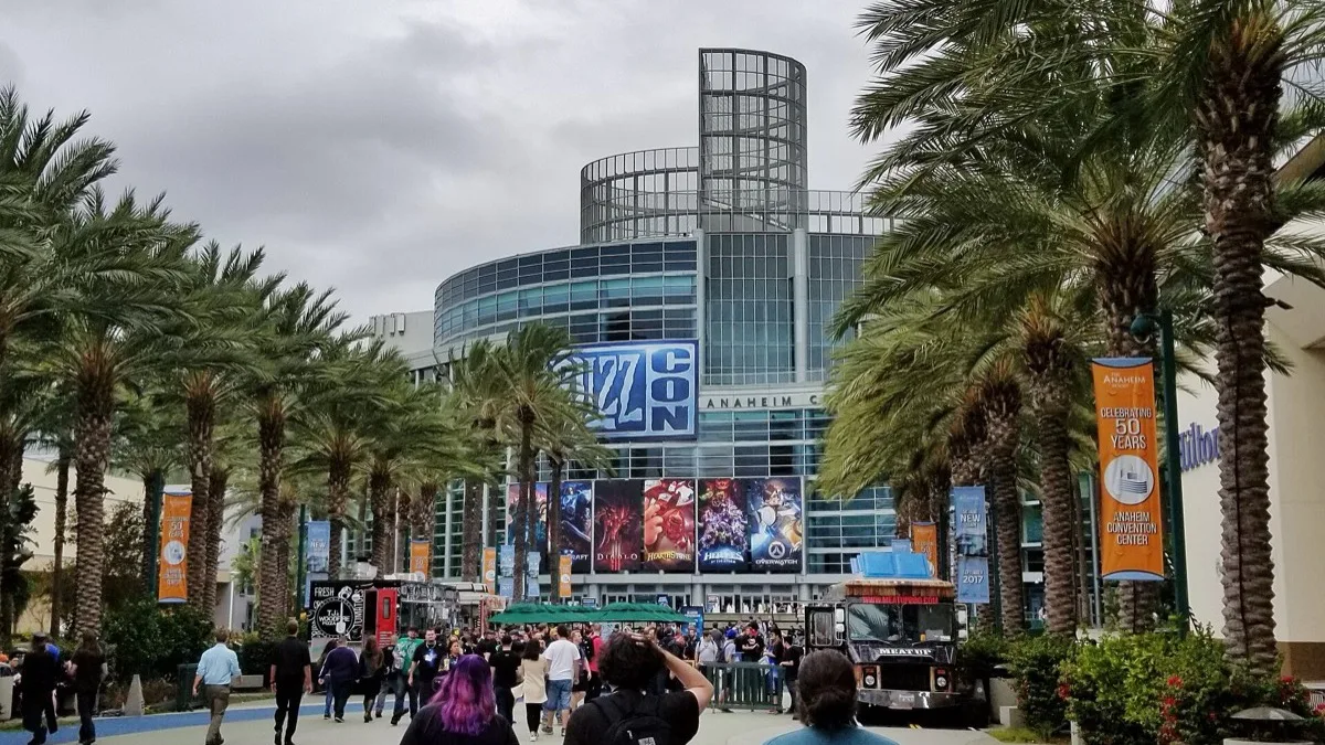 Crowds walking toward the Anaheim Convention Center under a large BlizzCon banner and palm trees