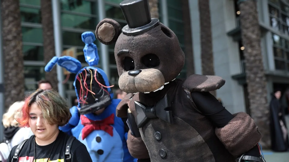 Two fans in homemade Freddy Fazbear and Bonnie costumes walking outside a convention centre