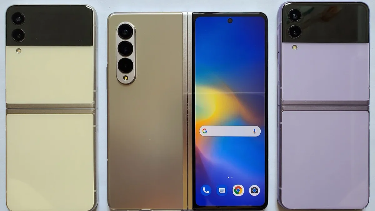 A Samsung Galaxy Z Fold opened flat between two closed Galaxy Z Flip clamshells in cream and purple