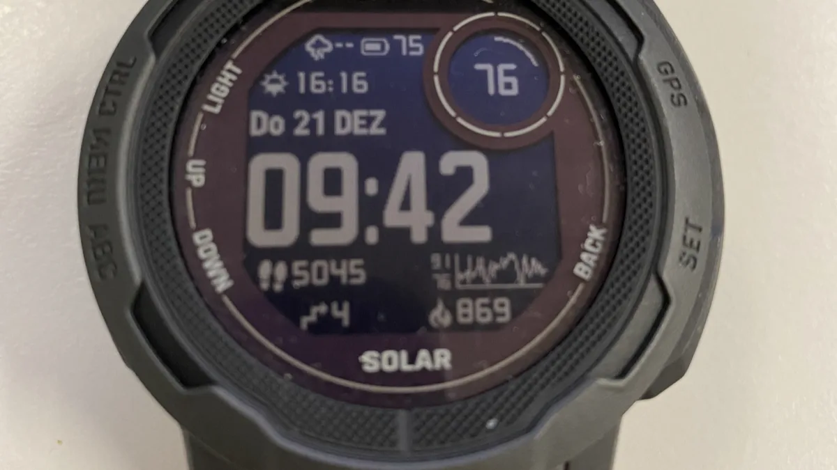 Close-up of a Garmin Instinct 2 Solar watch face showing step count, floors climbed and a heart rate graph