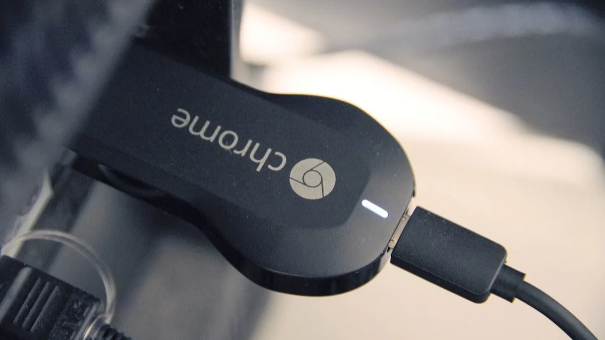 First-generation Google Chromecast dongle plugged into the HDMI port on the back of a television