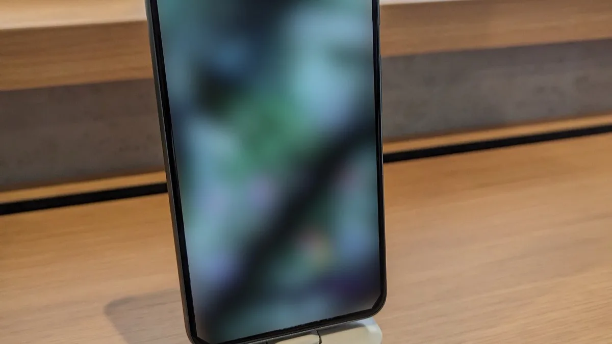 Google Pixel 8 standing on a wooden display shelf with a blurred image on its screen