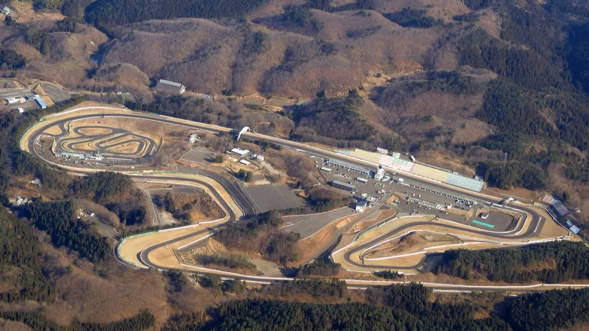 An aerial view of the Sportsland SUGO motor racing circuit in Miyagi, Japan, showing its looping layout cut into forested hills