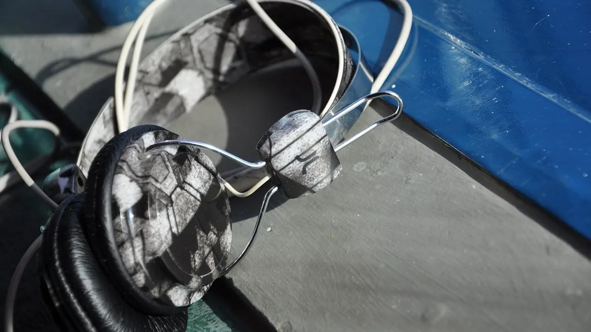 A pair of wired over-ear headphones resting on a painted wooden bench