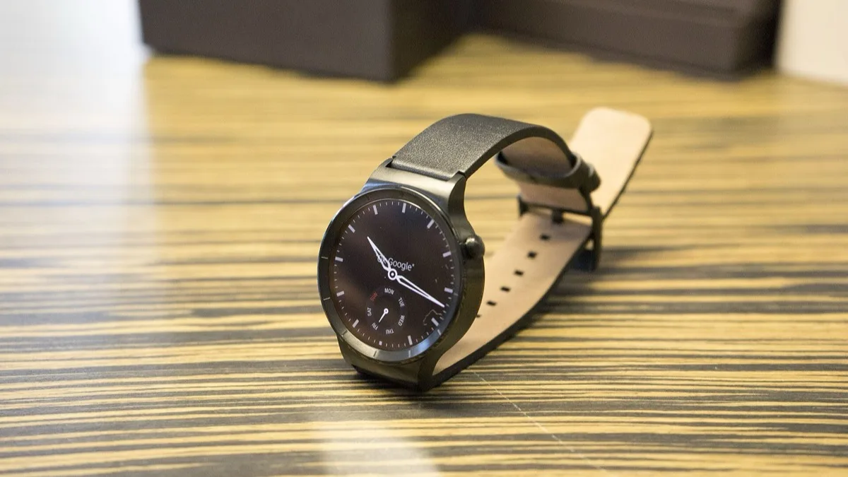 A Huawei smartwatch with a leather strap resting on a wooden table