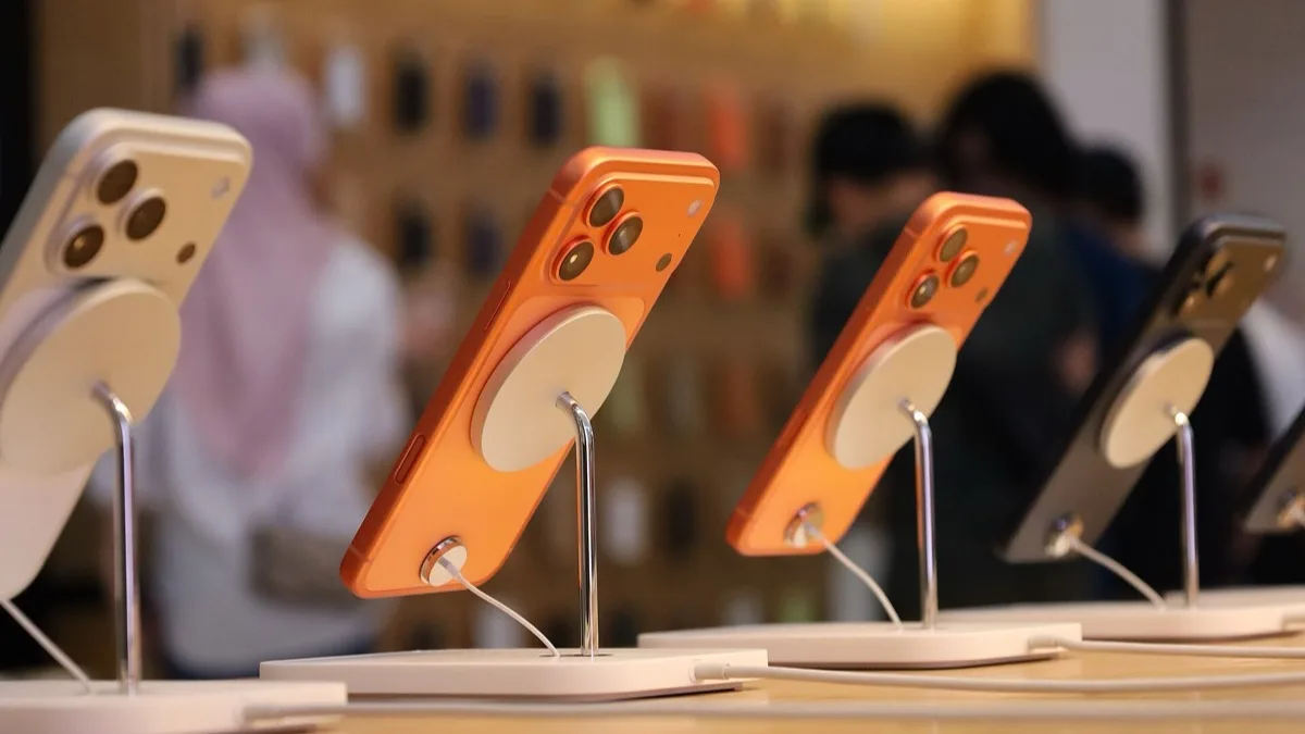 Orange and silver iPhone 17 Pro handsets on MagSafe display stands inside an Apple Store