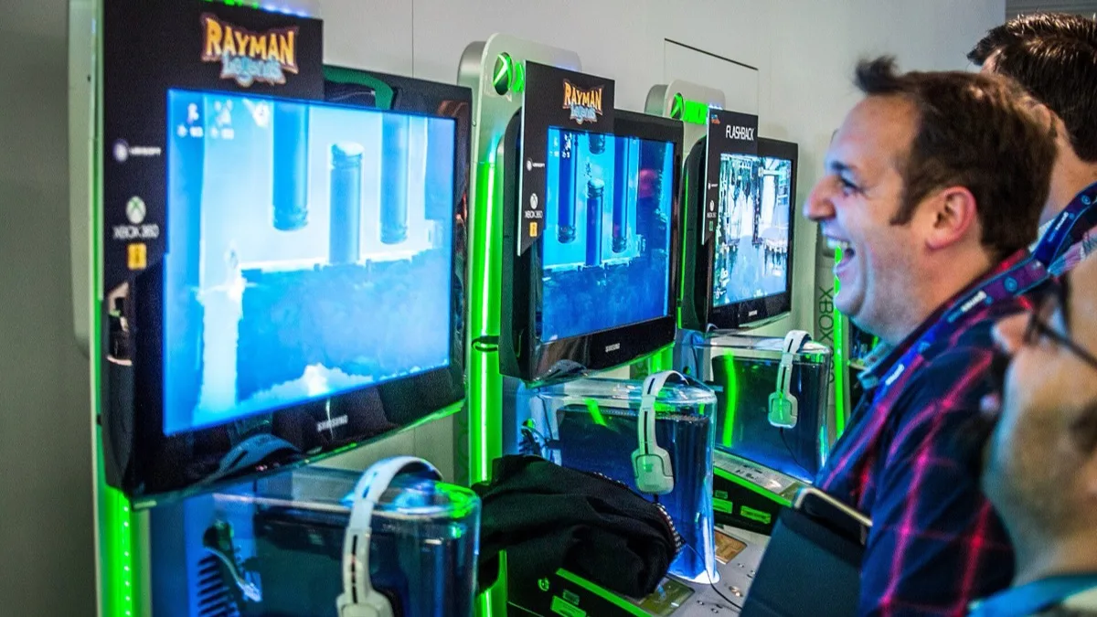 Visitors laughing as they play the original Rayman Legends on Xbox 360 demo kiosks at Gamescom 2013