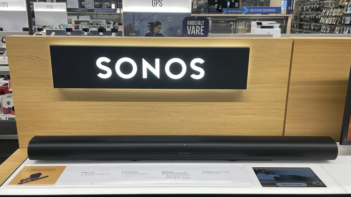 A Sonos soundbar on display beneath a lit Sonos logo sign in a retail store