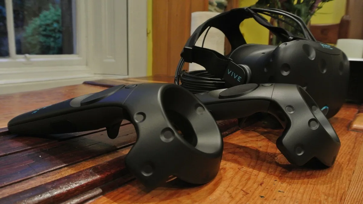 An HTC Vive virtual reality headset lying beside its two handheld motion controllers