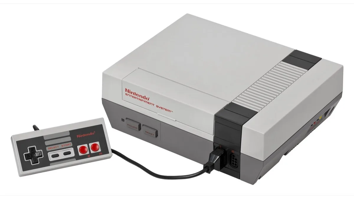 A grey Nintendo Entertainment System console sitting beside its rectangular NES controller
