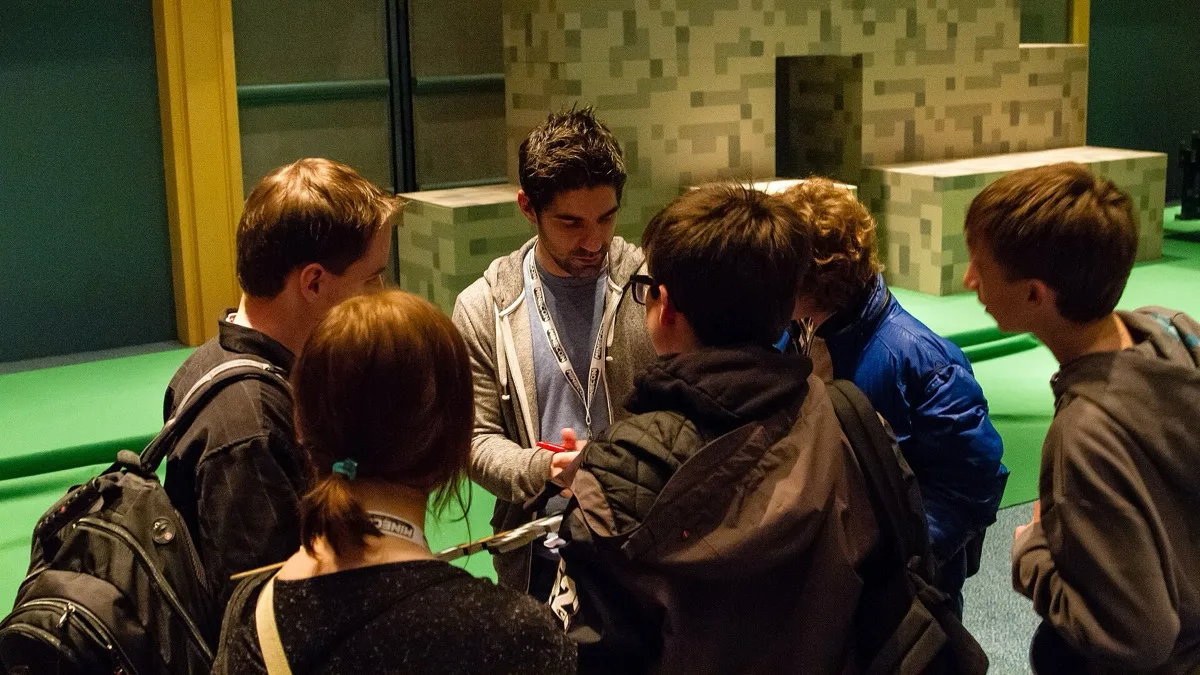 Minecraft players crowd around a creator signing autographs at a Minecraft fan convention