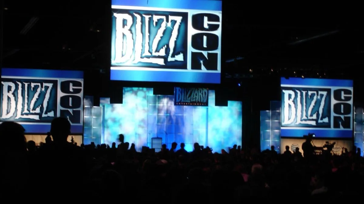 A crowd in silhouette facing three large BlizzCon screens and a Blizzard Entertainment stage at an earlier BlizzCon opening ceremony