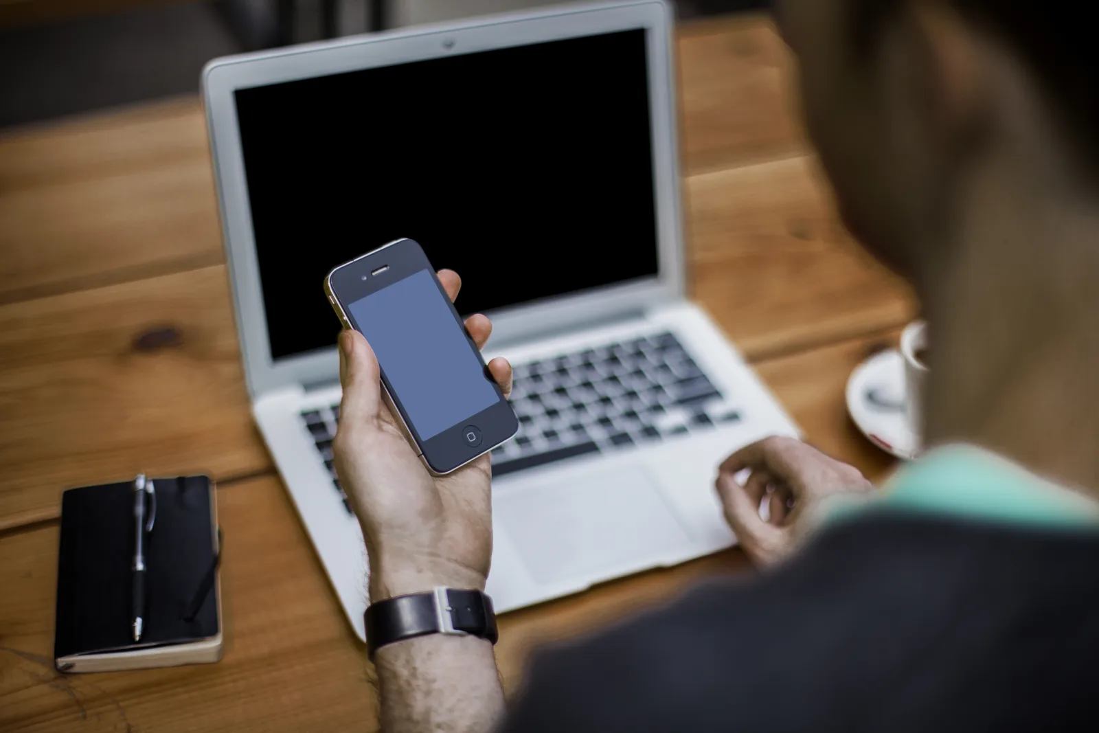 Person with a laptop and a phone on a desk, the setup used to copy owned PC games onto Android for Winlator