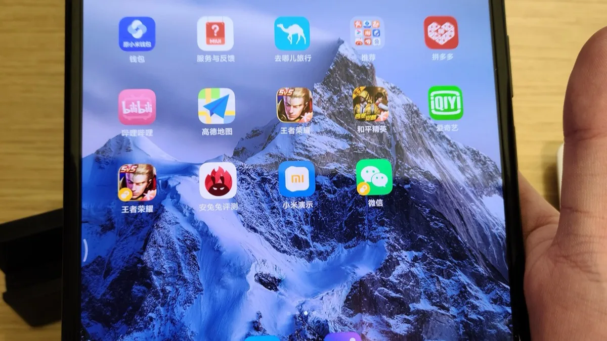 A hand holding an unfolded Xiaomi foldable phone showing its inner display with a Chinese home screen