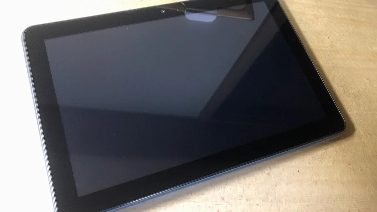An Amazon Fire HD 8 Plus tablet with its screen off, lying on a wooden desk