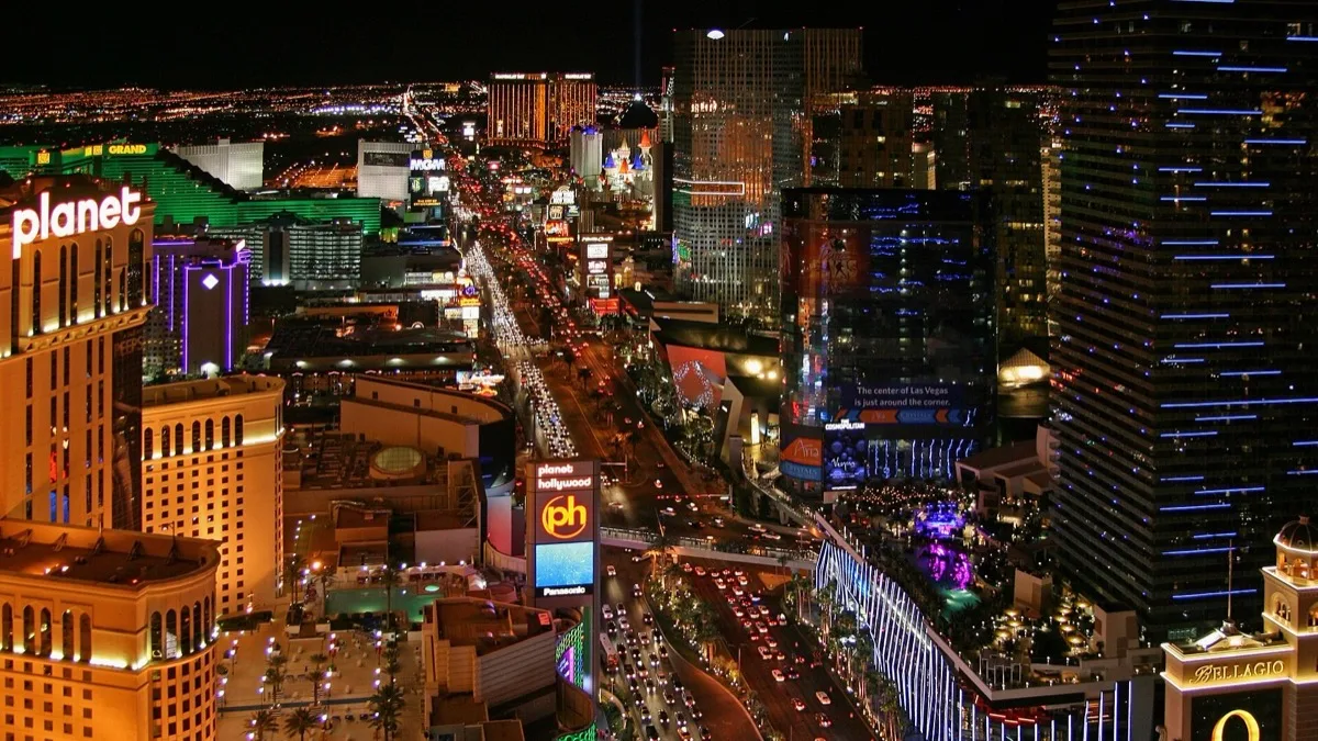 The Las Vegas Strip at night seen from above, with casino towers, the Bellagio sign and traffic lit along Las Vegas Boulevard