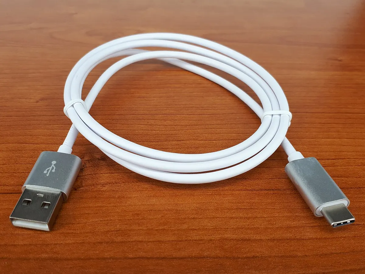 White USB-A to USB-C cable coiled on a wooden desk