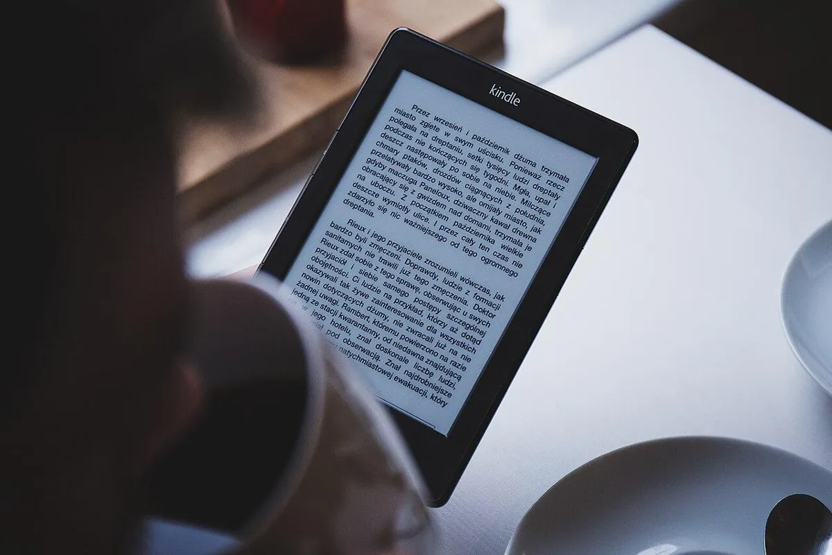 Kindle e-reader showing a page of text next to a cup of coffee