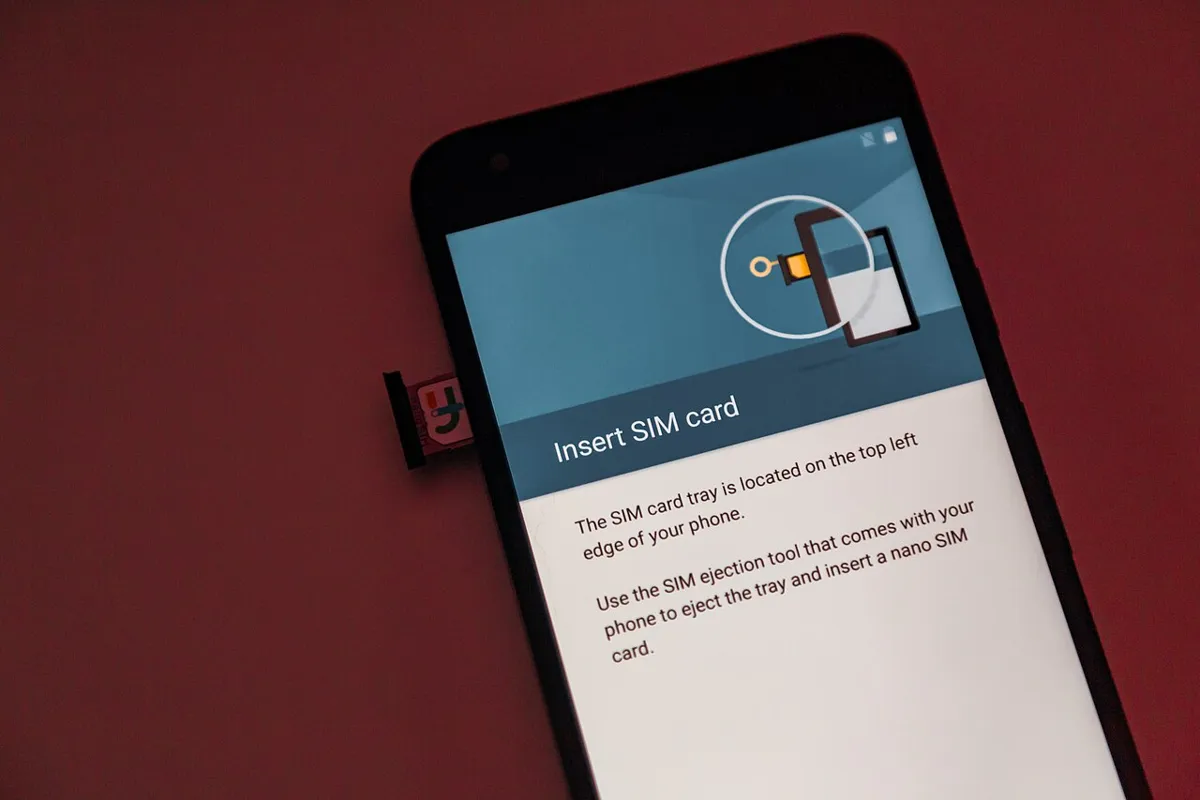 Android phone showing the Insert SIM card setup screen with its nano SIM tray pulled out beside it